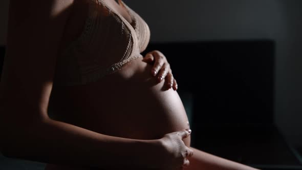 Silhouette of pregnant woman holds hands on belly