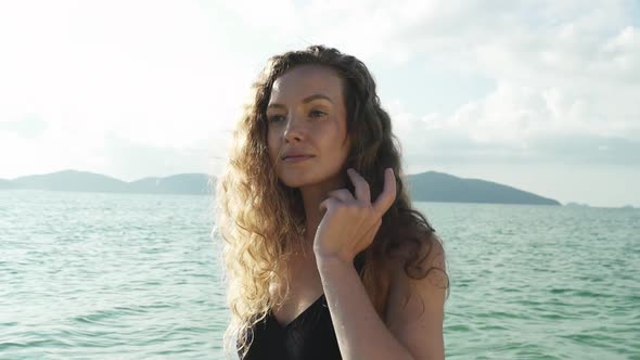 Model Wearing Swimsuit Looking Into Shore From Beach alt