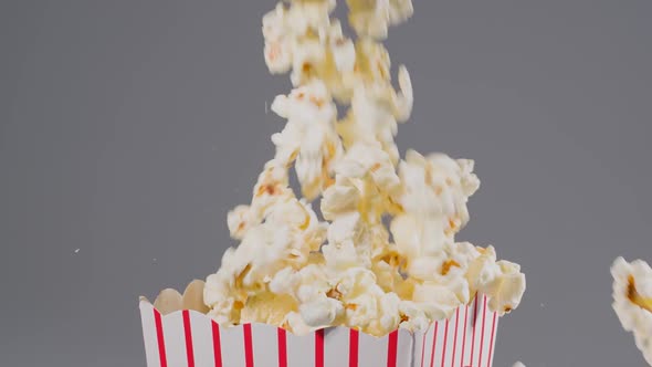 Popcorn falling in slow motion into a popcorn bucket alt