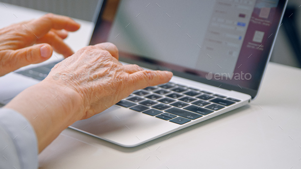 Old woman hands type on black keyboard of grey laptop Stock Photo by AboutImages