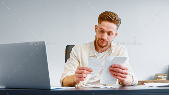 Bearded financial director analyzes paper checks searching for money