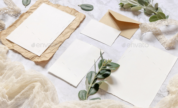 Wedding blank cards laying on a marble table decorated with eucalyptus branches