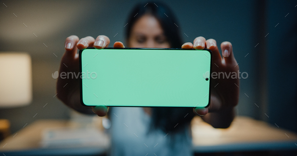 Young asia girl looking at camera, and show mock-up screen smartphone in house night. - Stock Photo - Images
