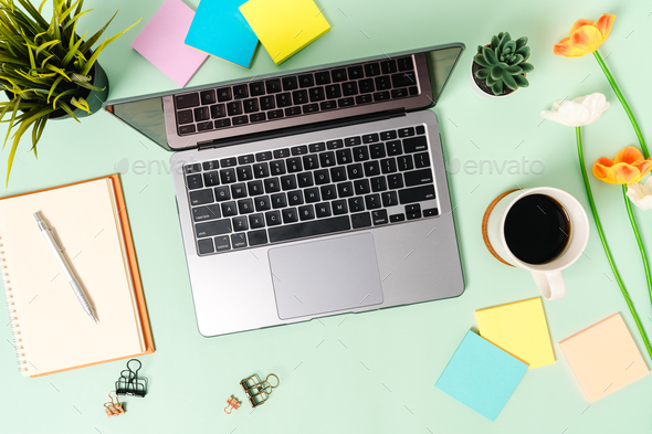 Top view office desk with laptop, coffee cup and open mockup black notebook  on green background. Stock Photo by Tirachard
