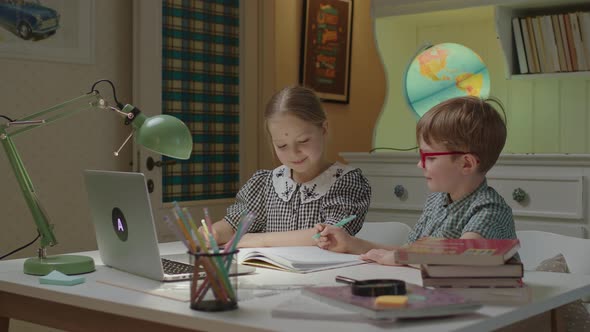 Schoolgirl Helping Her Younger Preschool Brother with Homework During Home Schooling