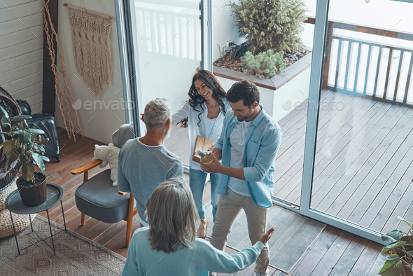 Top view of happy senior parents meeting young couple inside the house