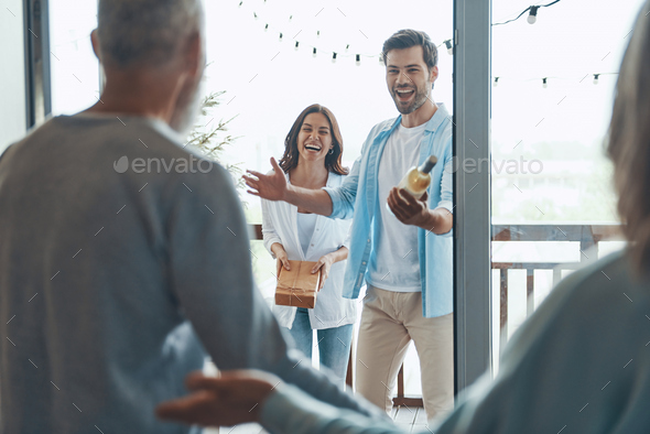 Happy senior parents meeting young couple inside the house