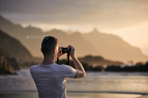 Man during photographing landscape with cliff at sunset - Stock Photo - Images