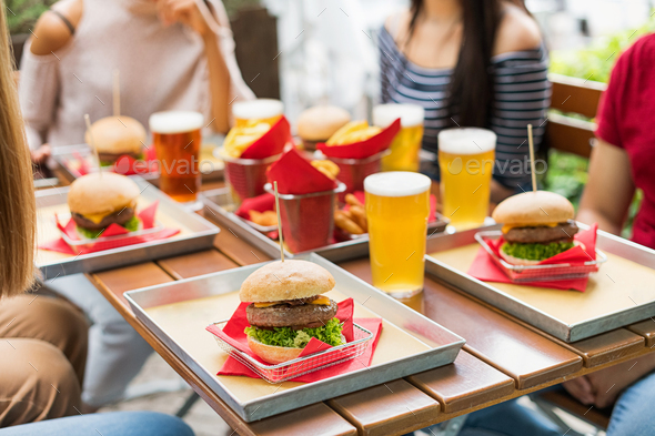 Serving of hamburgers and cold beers at a restaurant table - Stock Photo - Images