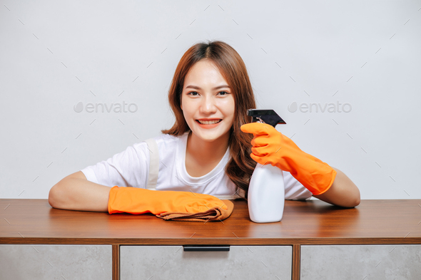 Asian pretty woman spraying and using cloth wipes on cabinets