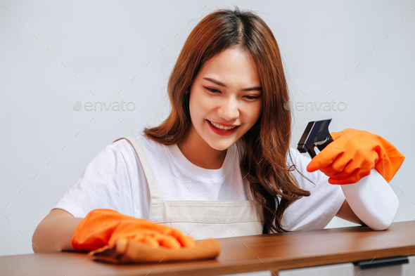 Asian pretty woman spraying and using cloth wipes on cabinets