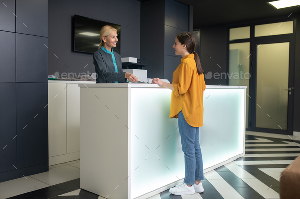 Blond receptionist in clinic greeting a new comer