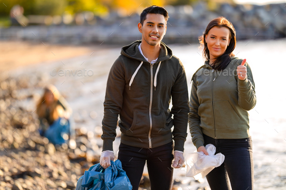 Team of young volunteers showing thumbs up at beach - Stock Photo - Images