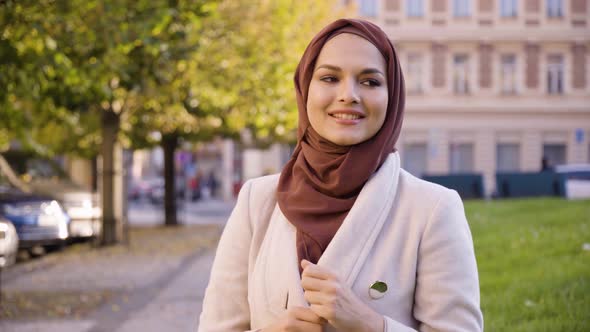 A Young Beautiful Muslim Woman Dances with a Smile in a Street in an Urban Area  Closeup alt