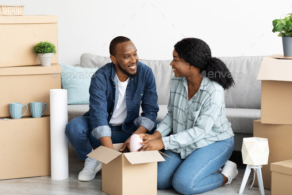 Happy young african american couple moving to new apartment, packing belongings