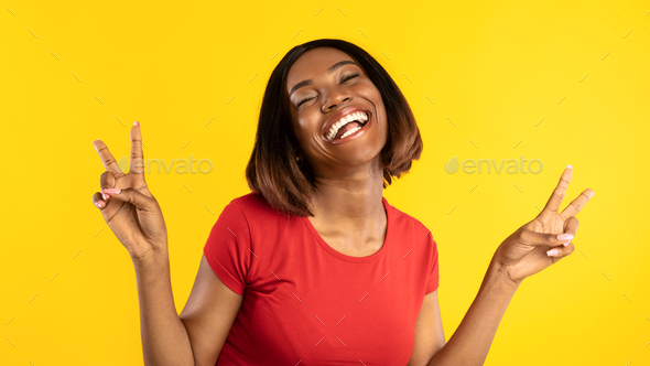 Happy Black Lady Gesturing Victory With Both Hands, Yellow Background