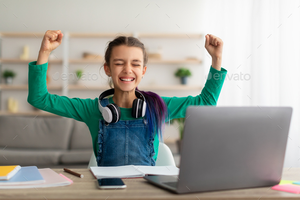 Portrait of emotional girl shaking fists using laptop