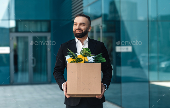 Come back to work after lockdown. Happy businessman with box of personal belongings going to office