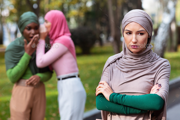Islamic Ladies Whispering Behind Back Of Their Unhappy Friend Outdoors