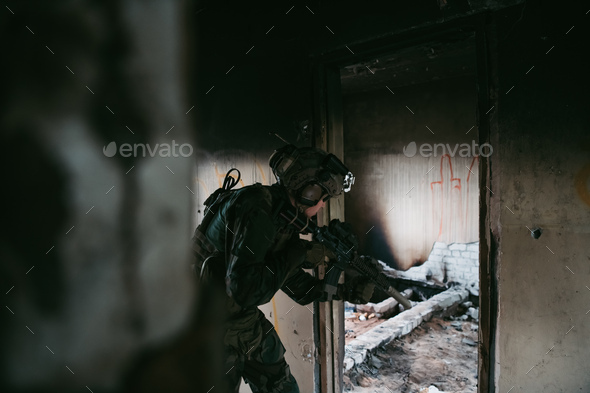 Military man with assault rifle standing inside building, he is ready for combat - Stock Photo - Images