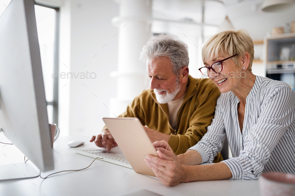 Senior couple websurfing on internet with laptop at home - Stock Photo - Images
