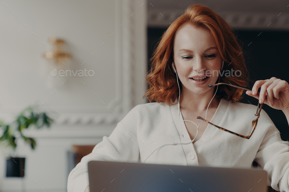 Pleased redhead woman student watches training webinar, - Stock Photo - Images
