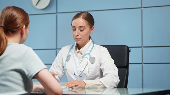 Young woman general practitioner explains lady hospital visitor prescription alt