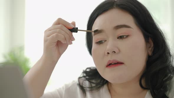 plus size Asian woman bloggers sitting are online to review cosmetic products via social media.