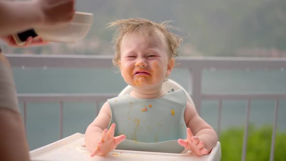 Mother Gives Baby Food From a Baby Spoon in a Restaurant a Child Eats Willingly alt