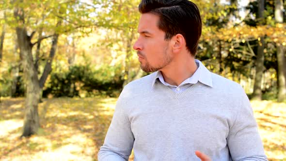 Young Man Stands in the Woods, Holds Head in Plams, Is Confused and Looks Around alt