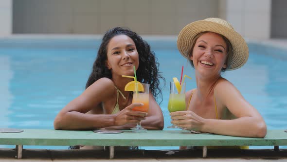 Two Happy Funny Multiracial Girlfriends Holding Exotic Nonalcoholic Ice Fruit Cocktails Making Cheer alt