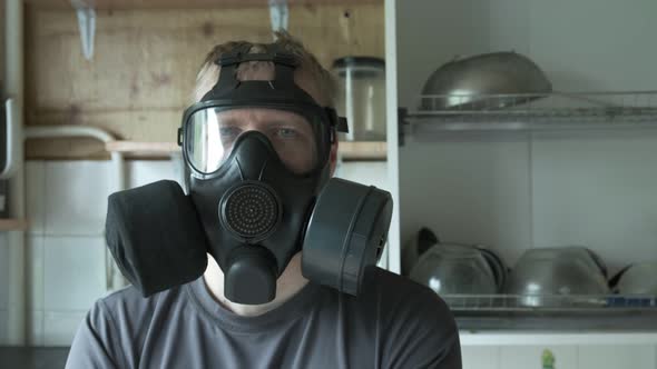 Man in Gas Mask Sitting at Kitchen at Home