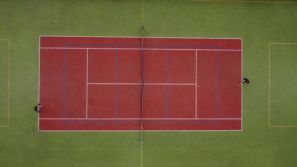Aerial view. Players are playing tennis on orange court.