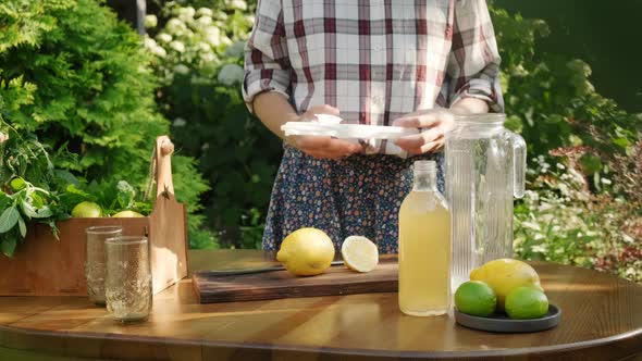 Woman Making Summer Lemonade Cocktail in Backyard Garden alt