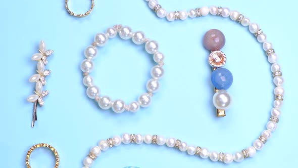 Flat Composition of Jewelry with Pearls Necklace Beads Rings Hairpins and Gems on a Blue Background