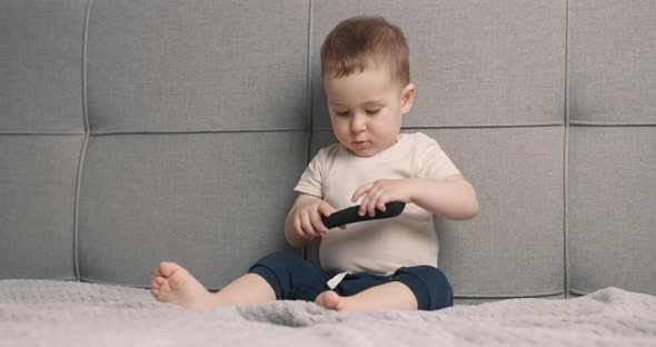 The Little Boy Sits on the Bed and Watching TV alt