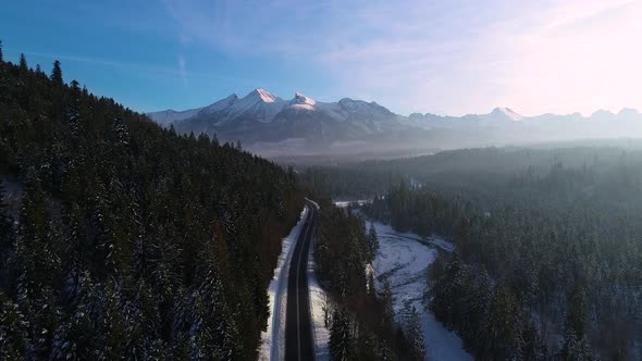 Aerial view of mountain twisted road in the winter and driving car. Cinematic drone shot