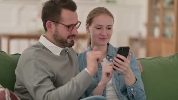 Happy Couple Using Smartphone Together at Home alt