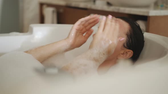 Pretty Woman Relaxing in a Bathtub Full with Foam