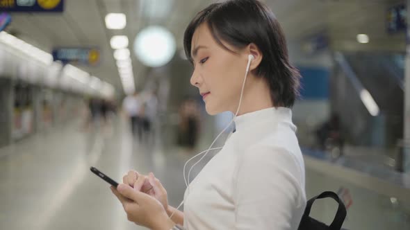 Portrait of asian woman with earphone listening music and using smartphone for chatting