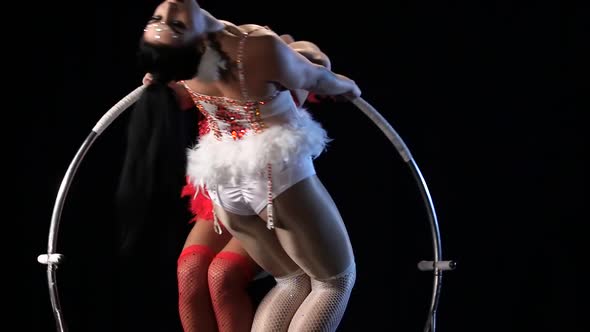 Gymnasts a Trick on the Aerial Hoop Metal Construction. Black Background. Slow Motion. Close Up alt