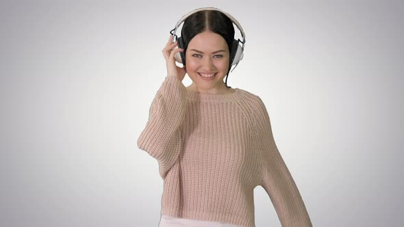 Smiling Female with Headphones Walking and Dancing To the Music on Gradient Background alt