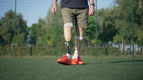 Front View Unrecognizable Amputee with Artificial Legs Playing Soccer in Slow Motion on Sunny Summer alt