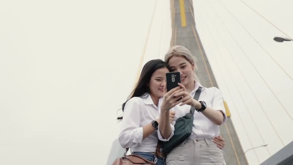 Happy Asian lesbian couples using smartphone selfies enjoying traveling in Thailand.