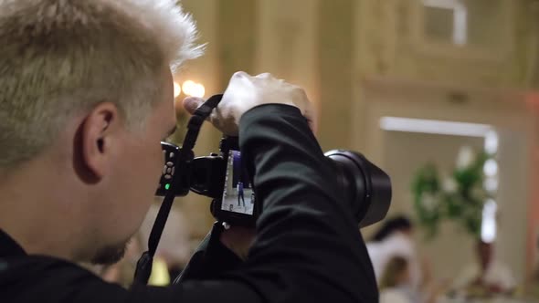 Man Photographer Takes Pictures in a Restaurant Party at Wedding Event alt