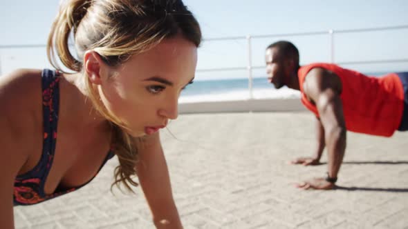 Couple doing push-up exercise on a promenade at beach 