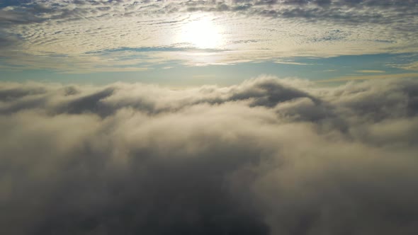Aerial View of Vibrant Yellow Sunrise Over White Dense Clouds with Blue Sky Overhead alt