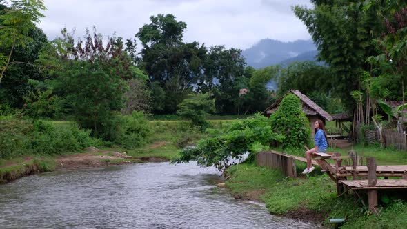 A young asian woman sitting by the river in rural village