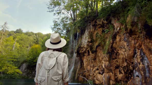 Young woman at the cascade of the waterfall on the mountain alt