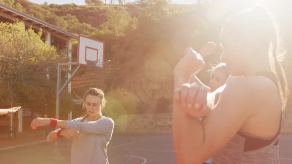 Diverse female basketball team wearing sportswear, stretching alt